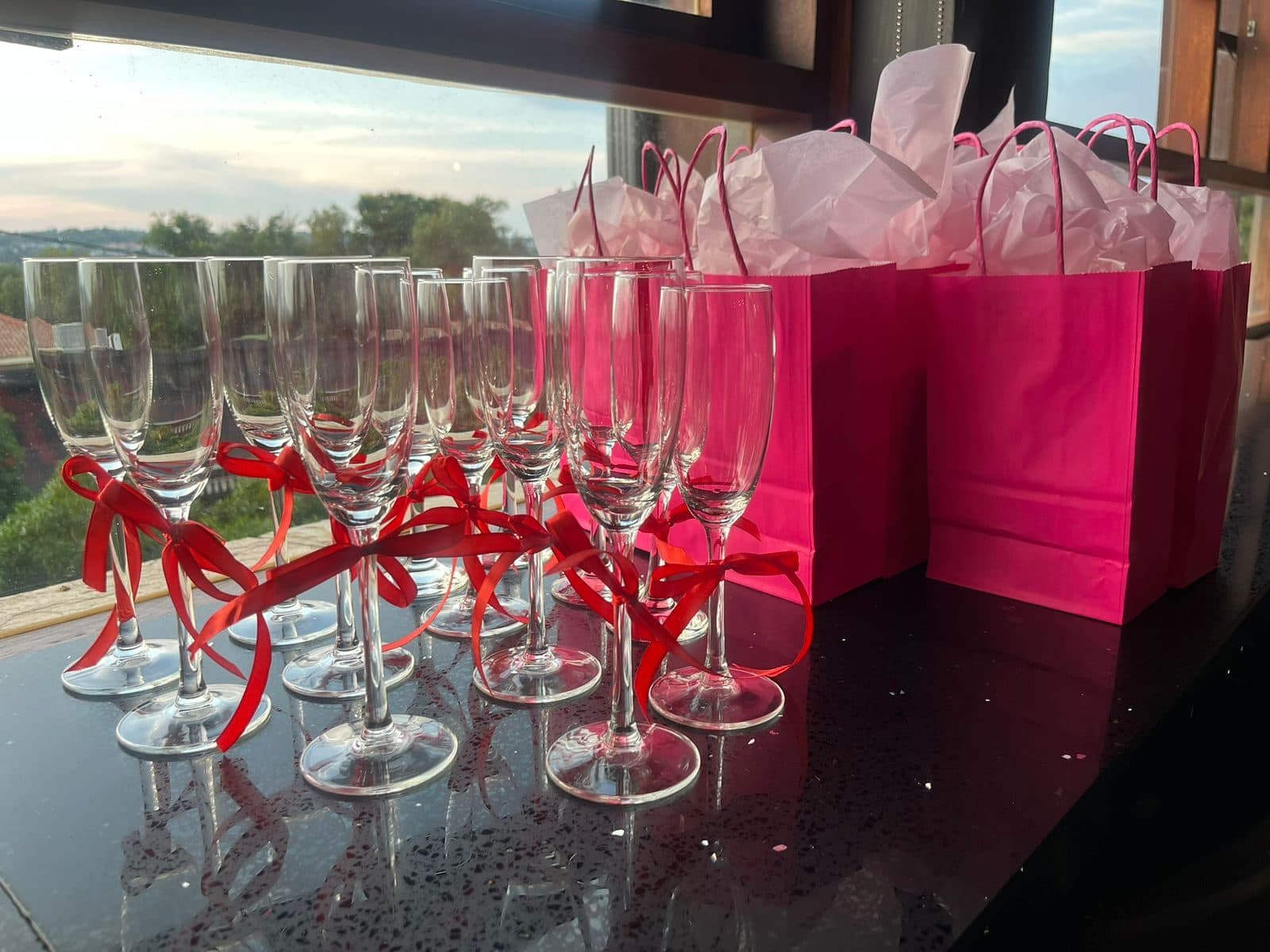 Hot-pink gift bags and ribboned champagne flutes at golden hour